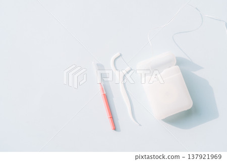 Interdental brush, floss pick and dental floss container on light blue background, oral care routine set Interdental brush, floss pick and dental floss container on light blue background, oral care routine set 137921969