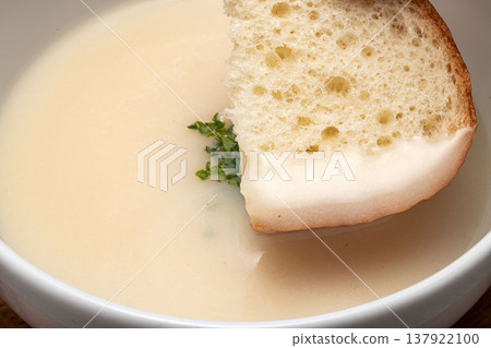 一張簡單而優雅的早餐/午餐圖片:白色碗中盛有奶油湯,配上烤麵包和香草裝飾。 一張簡單而優雅的早餐/午餐圖片:白色碗中盛有奶油湯,配上烤麵包和香草裝飾。 137922100