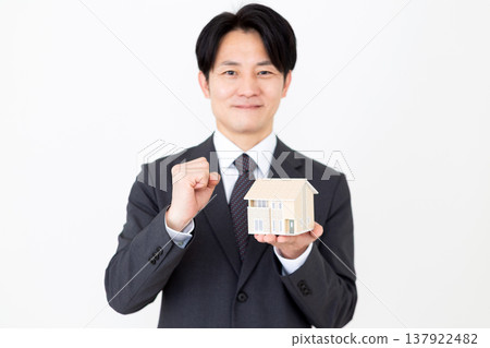 一位中年商人手持獨立式住宅模型，擺出勝利的姿態。 137922482