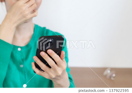 Woman looking at smartphone (image of presbyopia) 137922595