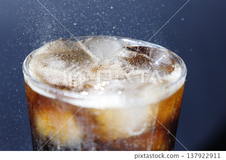 將氣泡可樂倒入玻璃杯中。 將氣泡可樂倒入玻璃杯中。 137922911