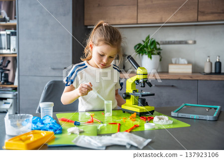 Girl using pipette to collect chemical solution during crystal growing experiment at home laboratory table. Practical chemistry activity and early STEM education through hands on scientific work Girl using pipette to collect chemical solution during crystal growing experiment at home laboratory table. Practical chemistry activity and early STEM education through hands on scientific work 137923106