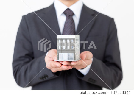 一位中年商人手持企業辦公大樓的住宅模型。 137923345