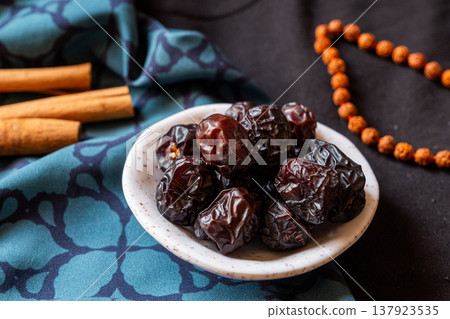 A close-up of two plates containing dates and walnuts, accompanied by cinnamon sticks prepared for Iftar at Ramadan. The scene highlights healthy snacks and natural ingredients. A close-up of two plates containing dates and walnuts, accompanied by cinnamon sticks prepared for Iftar at Ramadan. The scene highlights healthy snacks and natural ingredients. 137923535