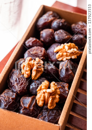 A close-up of two plates containing dates and walnuts, accompanied by cinnamon sticks prepared for Iftar at Ramadan. The scene highlights healthy snacks and natural ingredients. A close-up of two plates containing dates and walnuts, accompanied by cinnamon sticks prepared for Iftar at Ramadan. The scene highlights healthy snacks and natural ingredients. 137923553