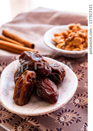 A close-up of two plates containing dates and walnuts, accompanied by cinnamon sticks prepared for Iftar at Ramadan. The scene highlights healthy snacks and natural ingredients. A close-up of two plates containing dates and walnuts, accompanied by cinnamon sticks prepared for Iftar at Ramadan. The scene highlights healthy snacks and natural ingredients. 137923581