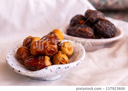 A close-up of two plates containing dates and walnuts, accompanied by cinnamon sticks prepared for Iftar at Ramadan. The scene highlights healthy snacks and natural ingredients. A close-up of two plates containing dates and walnuts, accompanied by cinnamon sticks prepared for Iftar at Ramadan. The scene highlights healthy snacks and natural ingredients. 137923600