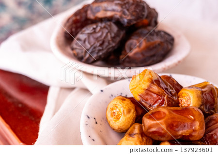 A close-up of two plates containing dates and walnuts, accompanied by cinnamon sticks prepared for Iftar at Ramadan. The scene highlights healthy snacks and natural ingredients. A close-up of two plates containing dates and walnuts, accompanied by cinnamon sticks prepared for Iftar at Ramadan. The scene highlights healthy snacks and natural ingredients. 137923601