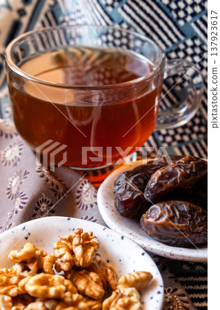 A close-up of two plates containing dates and walnuts, accompanied by cinnamon sticks prepared for Iftar at Ramadan. The scene highlights healthy snacks and natural ingredients. A close-up of two plates containing dates and walnuts, accompanied by cinnamon sticks prepared for Iftar at Ramadan. The scene highlights healthy snacks and natural ingredients. 137923617