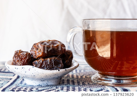A close-up of two plates containing dates and walnuts, accompanied by cinnamon sticks prepared for Iftar at Ramadan. The scene highlights healthy snacks and natural ingredients. A close-up of two plates containing dates and walnuts, accompanied by cinnamon sticks prepared for Iftar at Ramadan. The scene highlights healthy snacks and natural ingredients. 137923620