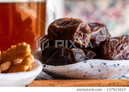 A close-up of two plates containing dates and walnuts, accompanied by cinnamon sticks prepared for Iftar at Ramadan. The scene highlights healthy snacks and natural ingredients. A close-up of two plates containing dates and walnuts, accompanied by cinnamon sticks prepared for Iftar at Ramadan. The scene highlights healthy snacks and natural ingredients. 137923625
