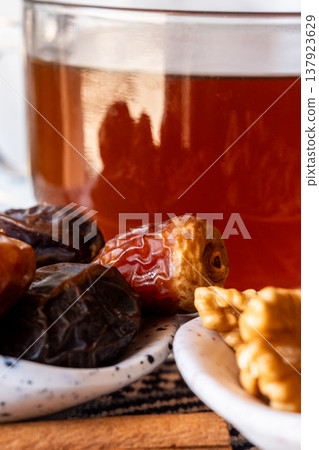 A close-up of two plates containing dates and walnuts, accompanied by cinnamon sticks prepared for Iftar at Ramadan. The scene highlights healthy snacks and natural ingredients. A close-up of two plates containing dates and walnuts, accompanied by cinnamon sticks prepared for Iftar at Ramadan. The scene highlights healthy snacks and natural ingredients. 137923629