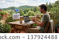 A man working from a cozy home office terrace with a view of nature, having a video call while an AI drone assistant delivers a document, relaxed and productive atmosphere. 137924488