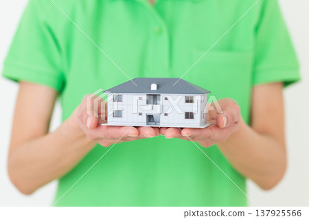 A middle-aged female care worker holding a model house. A middle-aged female care worker holding a model house. 137925566