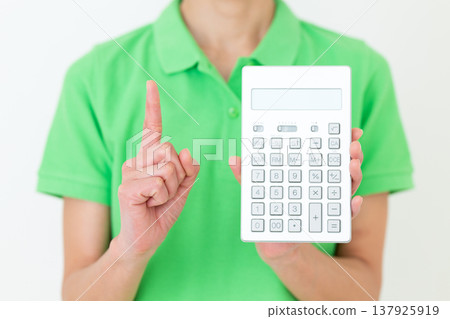 A middle-aged female care worker holding a calculator and raising her index finger. A middle-aged female care worker holding a calculator and raising her index finger. 137925919