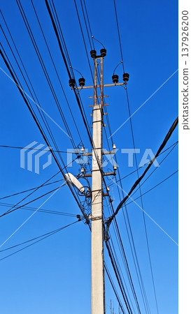 Utility pole with multiple electrical wires against a clear blue sky, showcasing the infrastructure of power distribution in an urban environment Utility pole with multiple electrical wires against a clear blue sky, showcasing the infrastructure of power distribution in an urban environment 137926200
