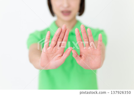 A middle-aged female care worker refuses, holding both hands out in front of her. A middle-aged female care worker refuses, holding both hands out in front of her. 137926350
