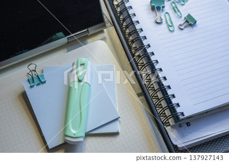 A desk with a highlighter, sticky notes and a spiral-bound notebook creating a theme of wortk and productivity A desk with a highlighter, sticky notes and a spiral-bound notebook creating a theme of wortk and productivity 137927143