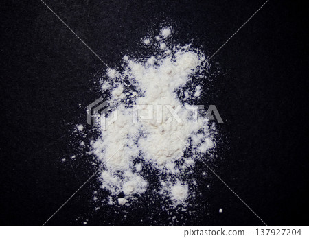 White flour scattered on a black background. Zenithal photo White flour scattered on a black background. Zenithal photo 137927204