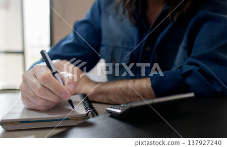 Close up shot of engineer at his desk.Horizontal shot of hands of a man writing Close up shot of engineer at his desk.Horizontal shot of hands of a man writing 137927240