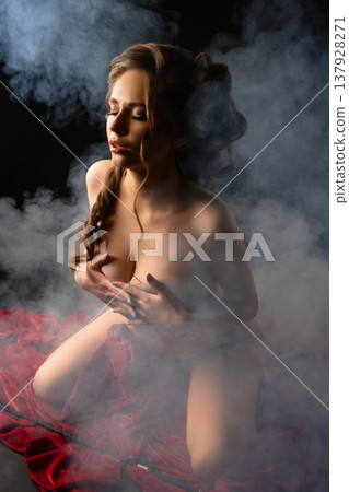Sensual woman with an elegant hairstyle kneeling in smoke on red velvet fabric. Sensual woman with an elegant hairstyle kneeling in smoke on red velvet fabric. 137928271