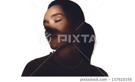Female portrait with pearl necklace in dramatic shadow light luxury style. Female portrait with pearl necklace in dramatic shadow light luxury style. 137928356