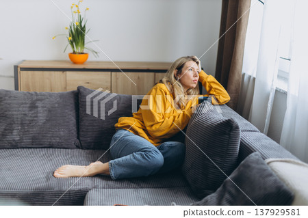 Lonely woman feeling emotional burnout and depression sitting on sofa at home after breakup with quiet isolation and mental fatigue Lonely woman feeling emotional burnout and depression sitting on sofa at home after breakup with quiet isolation and mental fatigue 137929581
