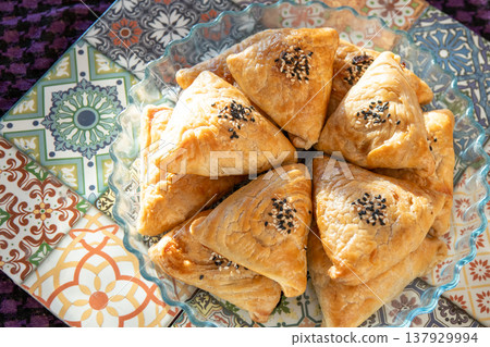 Samosa made from puff pastry. A triangular pie with meat filling with sesame seeds. Asian food Samosa made from puff pastry. A triangular pie with meat filling with sesame seeds. Asian food 137929994