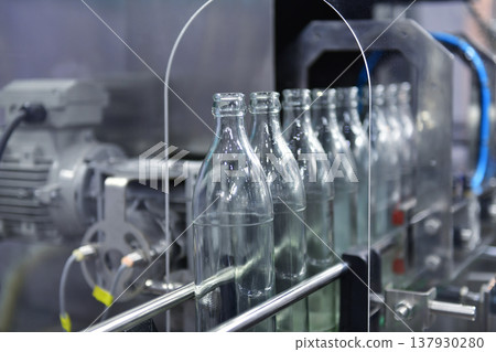 Conveyor belt with empty glass bottles in a modern bottling factory line Conveyor belt with empty glass bottles in a modern bottling factory line 137930280