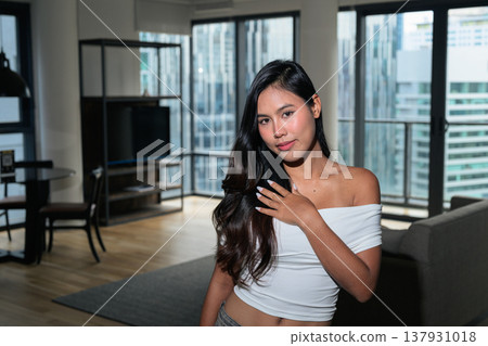 Young Asian woman standing in a modern high-rise apartment with city view in Kuala Lumpur, Malaysia Young Asian woman standing in a modern high-rise apartment with city view in Kuala Lumpur, Malaysia 137931018