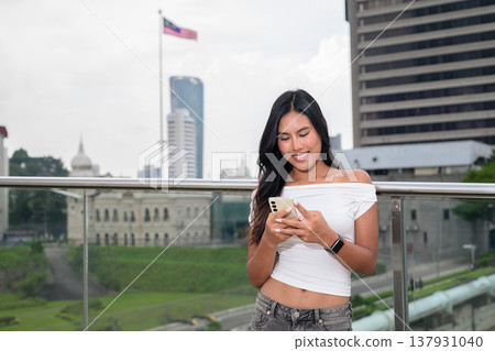 Portrait of woman against Kuala Lumpur city skyline with National Textile Museum and Malaysian flag Portrait of woman against Kuala Lumpur city skyline with National Textile Museum and Malaysian flag 137931040