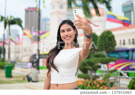 Thai Woman at Merdeka Square Kuala Lumpur using phone in front of the Sultan Abdul Samad Building. Thai Woman at Merdeka Square Kuala Lumpur using phone in front of the Sultan Abdul Samad Building. 137931065