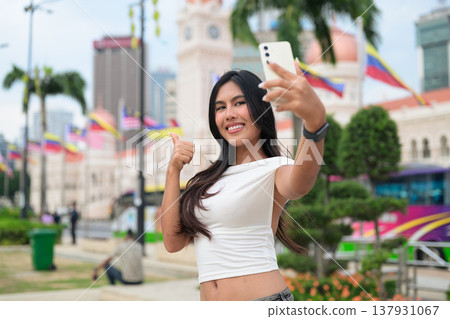 Thai Woman at Merdeka Square Kuala Lumpur using phone in front of the Sultan Abdul Samad Building. Thai Woman at Merdeka Square Kuala Lumpur using phone in front of the Sultan Abdul Samad Building. 137931067