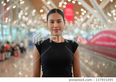 A portrait of a smiling young Asian woman wearing a black t-shirt in a modern airport terminal A portrait of a smiling young Asian woman wearing a black t-shirt in a modern airport terminal 137931095
