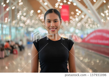A portrait of a smiling young Asian woman wearing a black t-shirt in a modern airport terminal A portrait of a smiling young Asian woman wearing a black t-shirt in a modern airport terminal 137931096