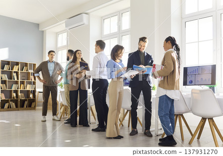 Team of coworkers in modern office discussing documents, data and strategy Team of coworkers in modern office discussing documents, data and strategy 137931270
