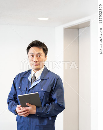 A male facility manager holding a tablet in the elevator lobby. 137932899