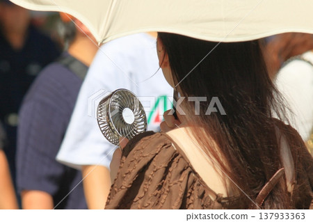 A woman walking with a handheld fan A woman walking with a handheld fan 137933363