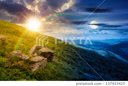 day meet night on summer solstice landscape in mountains. sun and moon over grassy hill with huge stones under the epic sky. wonderful nature background. picture of a hillside meadow near the peak 137933425