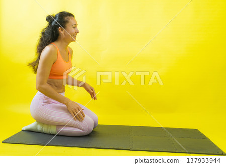 Woman kneeling on yoga mat smiling, feeling good Woman kneeling on yoga mat smiling, feeling good 137933944
