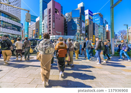 日本東京的城市景觀：銀座持續吸引入境遊客。熙熙攘攘的銀座四丁目十字路口。背景中是正在拆除的三愛夢想中心。 137936908