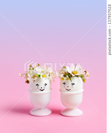 White Easter eggs with funny face with spring pear and strawberry flowers on a pink blue gradient background. Happy Easter concept. Greeting card. White Easter eggs with funny face with spring pear and strawberry flowers on a pink blue gradient background. Happy Easter concept. Greeting card. 137937028