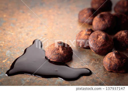 Chocolate truffles and chocolate sauce against a rusty background. Chocolate truffles and chocolate sauce against a rusty background. 137937147
