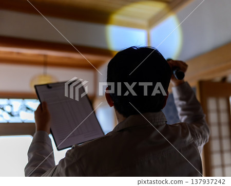 一名男子用手電筒照向天花板。 137937242