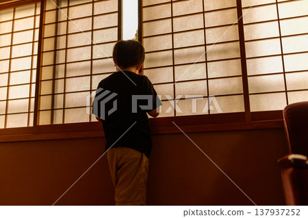 一個男孩透過障子門向外望去 137937252