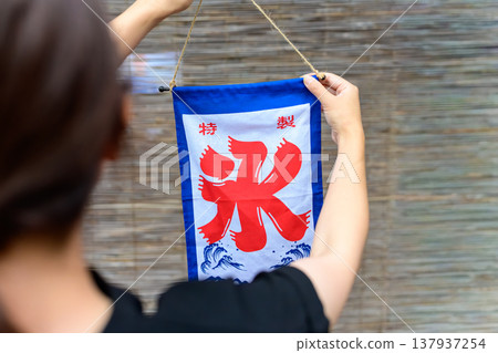 一個人在竹簾前舉著一面特製的刨冰旗。 137937254