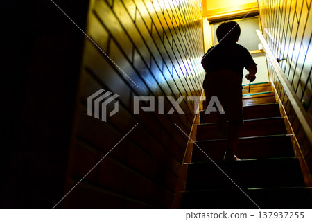 Silhouette of a child climbing a dimly lit staircase 137937255