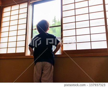 The back of a boy looking outside through a shoji screen. The back of a boy looking outside through a shoji screen. 137937323