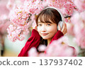 一位年輕女子在櫻花樹下戴著耳機聽音樂。 137937402