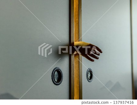 A hand reaching out through the gap in the sliding door A hand reaching out through the gap in the sliding door 137937416